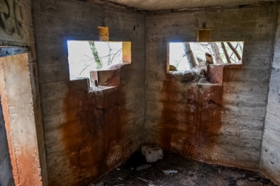 Inside the Bunker. To the left is the open doorway you pass through to gain entrance into it. Ahead of you, cut into the slant-angled forward-facing sides of the bunker, a pair of curious openings. The story behind this architecture is chilling in the extreme. The front faces were slanted to either side, when viewed from the direction of incoming hostile fire, laid down by an amphibious invasion force, as a deflection measure for incoming machine-gun or artillery rounds. The pair of openings are designed to hold the swiveling mounts for 50-caliber machine guns which would be getting used to return fire in an attempt to kill those who were coming ashore below, making their way inland, killing everybody they encountered as they did so. Pear Harbor had been attacked, and World War II was just begun. The fear hovering in the Hawaiian air of the time was thick and palpable, and no one knew what was coming next. Photo by James MacLaren. Inside the Bunker. To the left is the open doorway you pass through to gain entrance into it. Ahead of you, cut into the slant-angled forward-facing sides of the bunker, a pair of curious openings. The story behind this architecture is chilling in the extreme. The front faces were slanted to either side, when viewed from the direction of incoming hostile fire, laid down by an amphibious invasion force, as a deflection measure for incoming machine-gun or artillery rounds. The pair of openings are designed to hold the swiveling mounts for 50-caliber machine guns which would be getting used to return fire in an attempt to kill those who were coming ashore below, making their way inland, killing everybody they encountered as they did so. Pear Harbor had been attacked, and World War II was just begun. The fear hovering in the Hawaiian air of the time was thick and palpable, and no one knew what was coming next. Photo by James MacLaren.
